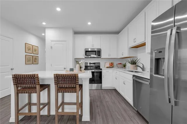 a kitchen with stainless steel appliances granite countertop a refrigerator a stove a sink dishwasher a dining table and chairs with wooden floor