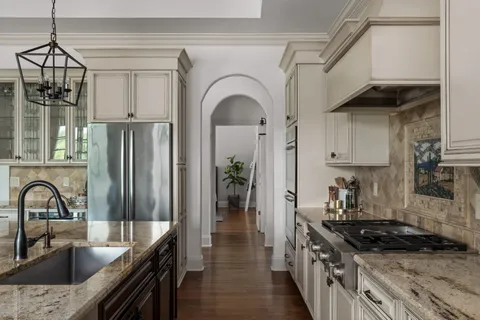 a kitchen with stainless steel appliances granite countertop a sink a stove and a refrigerator
