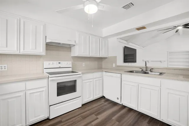 a kitchen with granite countertop white cabinets and white appliances