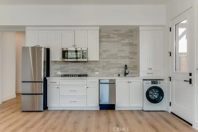 a kitchen with stainless steel appliances white cabinets and wooden floors
