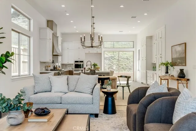 a living room with furniture kitchen area and large windows