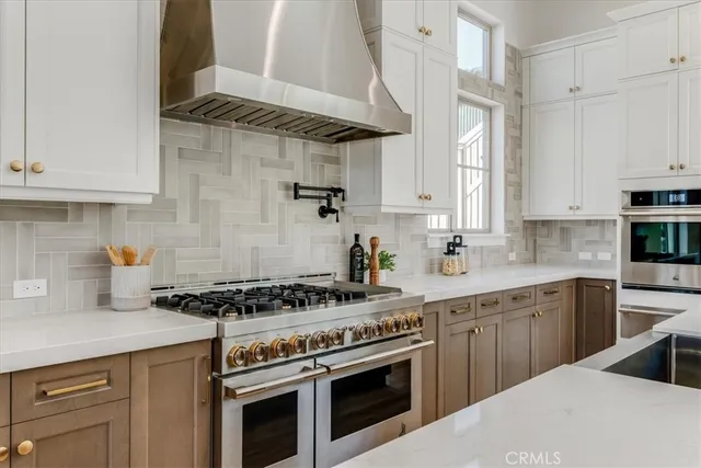 a kitchen with stainless steel appliances granite countertop a stove a sink and white cabinets