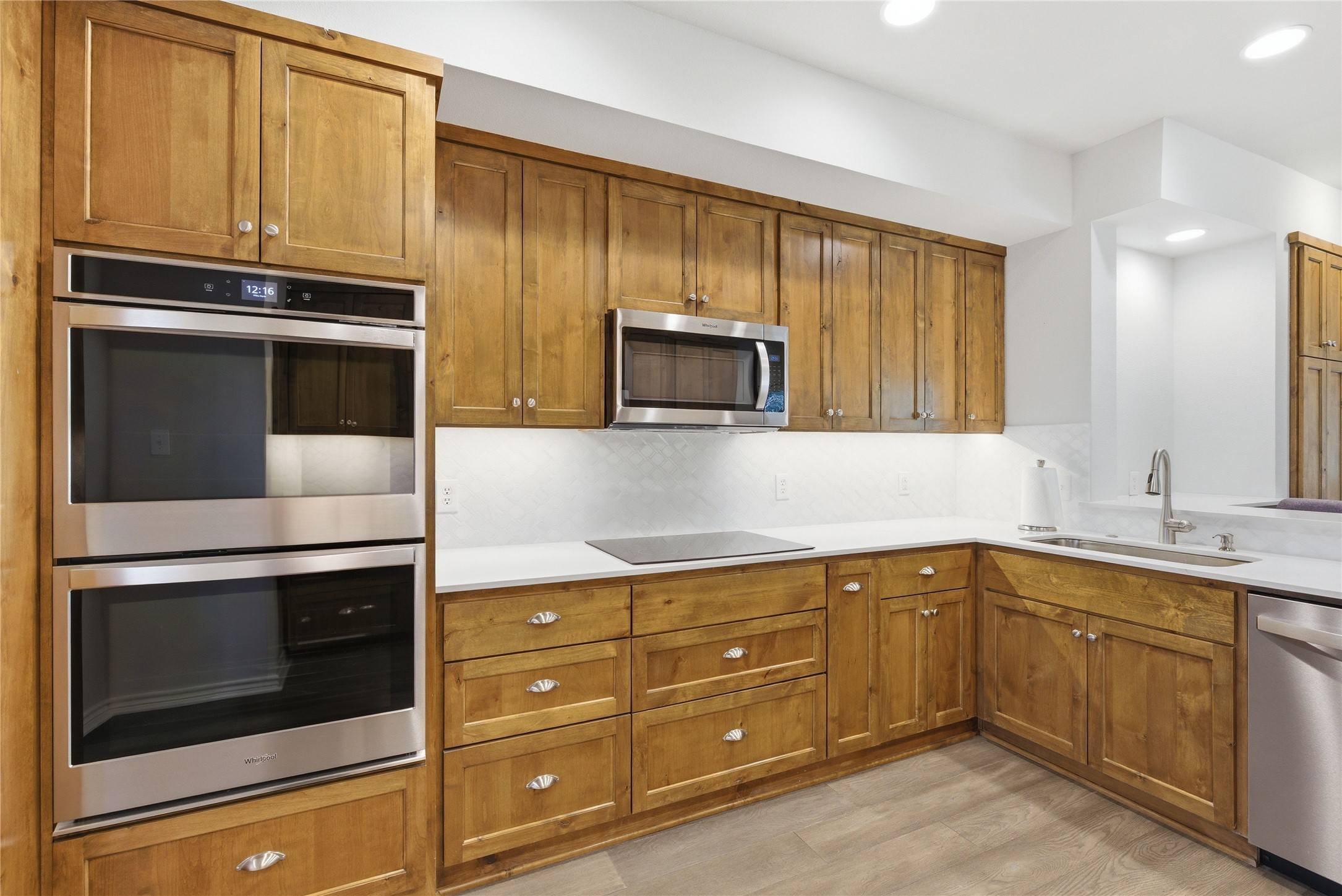 1204 Orlando Road Austin, TX 78733 - Photo 5 of 40 A contemporary kitchen showcasing natural wood cabinetry, integrated stainless steel appliances, and sleek countertops.