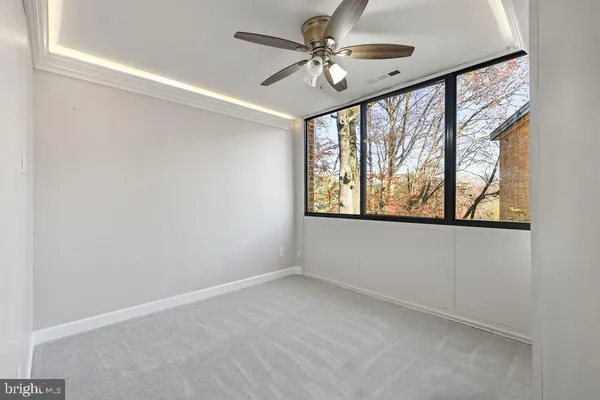 an empty room with windows and ceiling fan