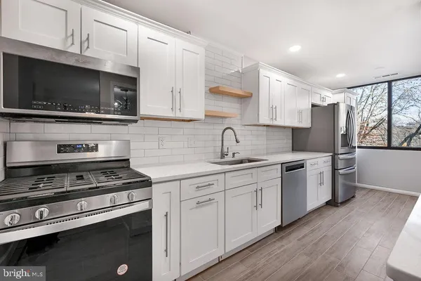 a kitchen with stainless steel appliances a stove microwave and sink
