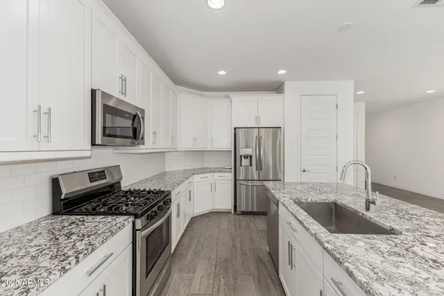 a kitchen with stainless steel appliances granite countertop a sink stove and refrigerator
