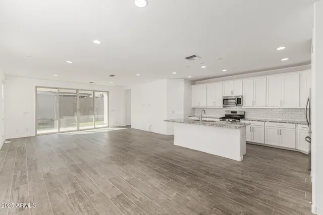 a large white kitchen with kitchen island a sink white cabinets and white appliances