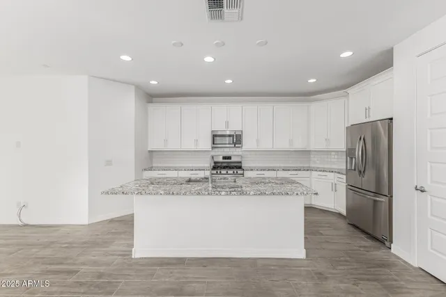 a large kitchen with stainless steel appliances granite countertop a stove a refrigerator a sink and a microwave