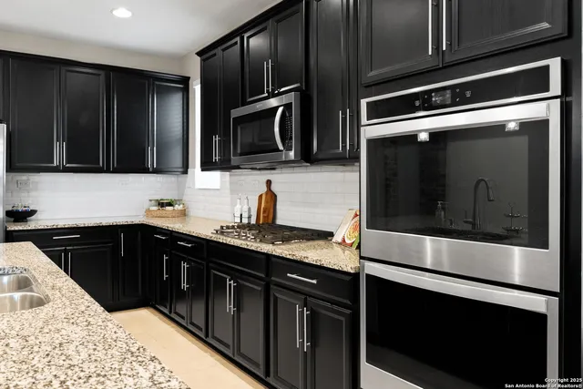 a kitchen with stainless steel appliances kitchen island granite countertop a stove microwave and refrigerator