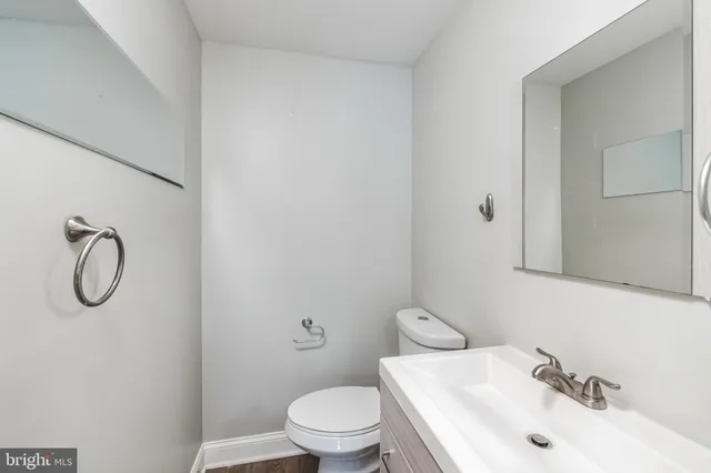 a bathroom with a toilet sink vanity and mirror