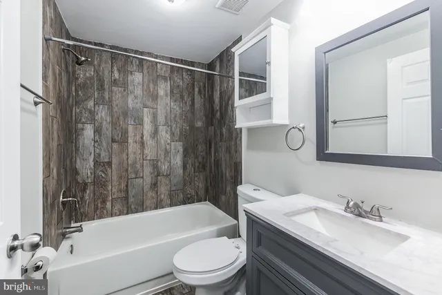 a bathroom with a granite countertop bathtub shower sink vanity mirror and toilet