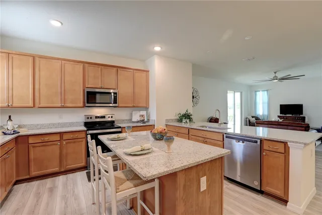 a kitchen with stainless steel appliances a stove top oven a sink dishwasher and a refrigerator with wooden floor