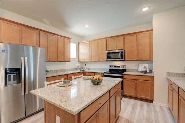 a kitchen with stainless steel appliances granite countertop a sink stove microwave and refrigerator