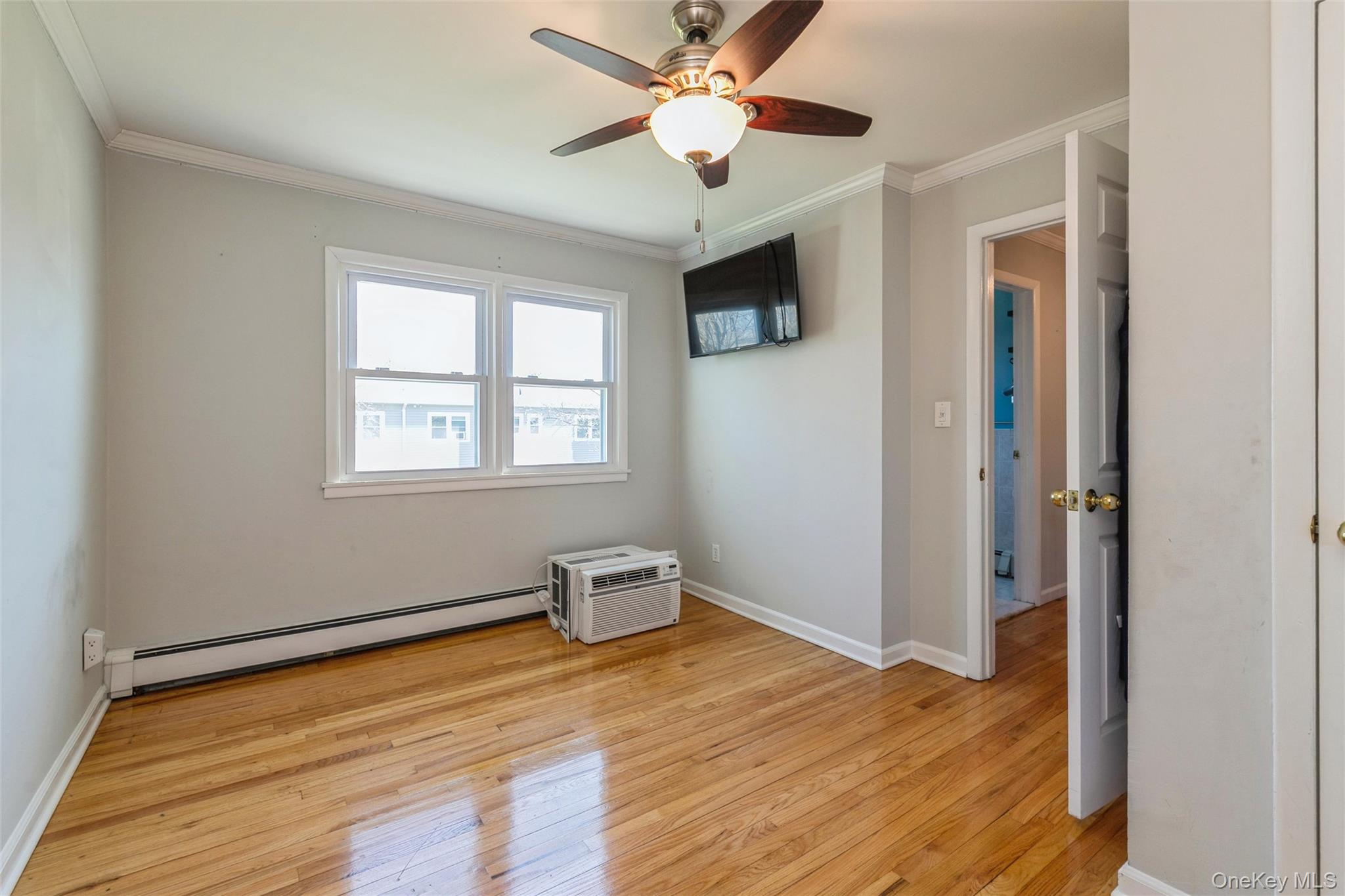 92 Cardinal Lane, Unit 92 Islip, NY 11751 - Photo 12 of 36 a view of an empty room with window and wooden floor