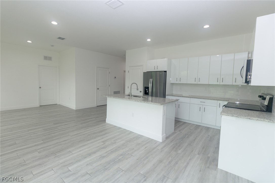 3032 West Briarwood Road LaBelle, FL 33935 - Photo 9 of 23 a kitchen with a sink wooden floor and white cabinets