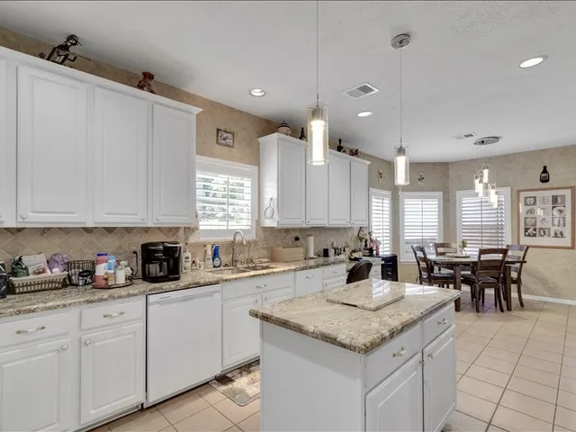 a large kitchen with granite countertop a stove refrigerator and cabinets