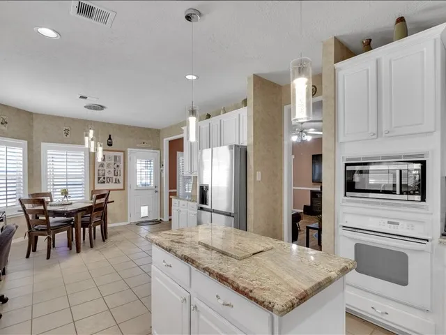 a kitchen with a stove a sink a kitchen island with chairs and white cabinets