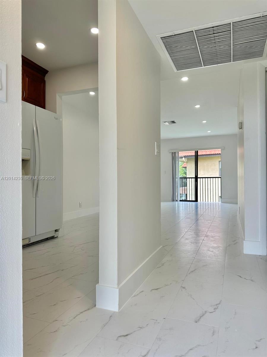 a view of a hallway with windows and chandelier