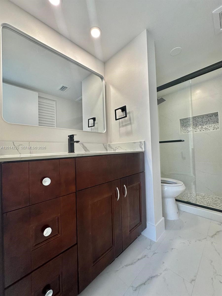 21911 Lake Forest Circle, Unit 202 Boca Raton, FL 33433 - Photo 11 of 14 a bathroom with a sink a toilet a mirror and shower