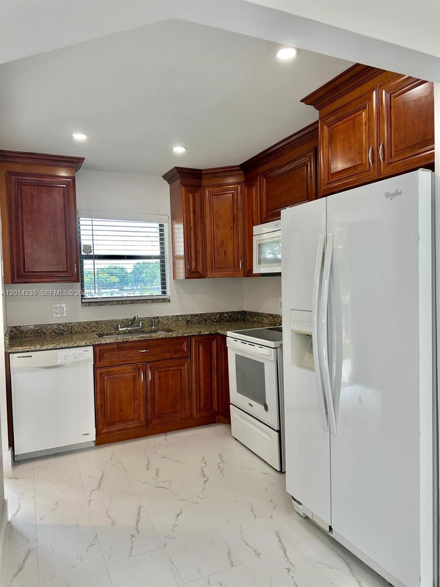 21911 Lake Forest Circle, Unit 202 Boca Raton, FL 33433 - Photo 4 of 14 a kitchen with granite countertop a refrigerator and a sink