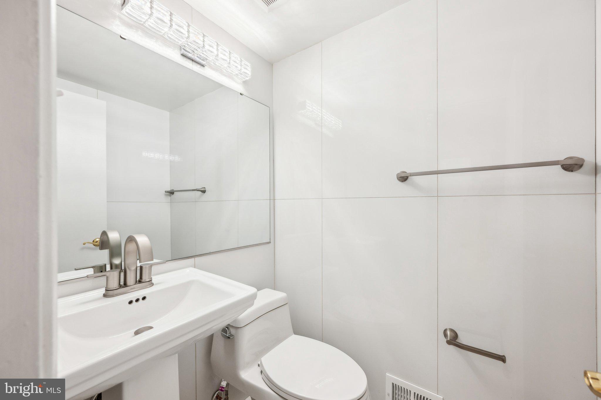 2827 Ellicott Street Northwest Washington, DC 20008 - Photo 31 of 56 a bathroom with a toilet a sink a mirror and vanity