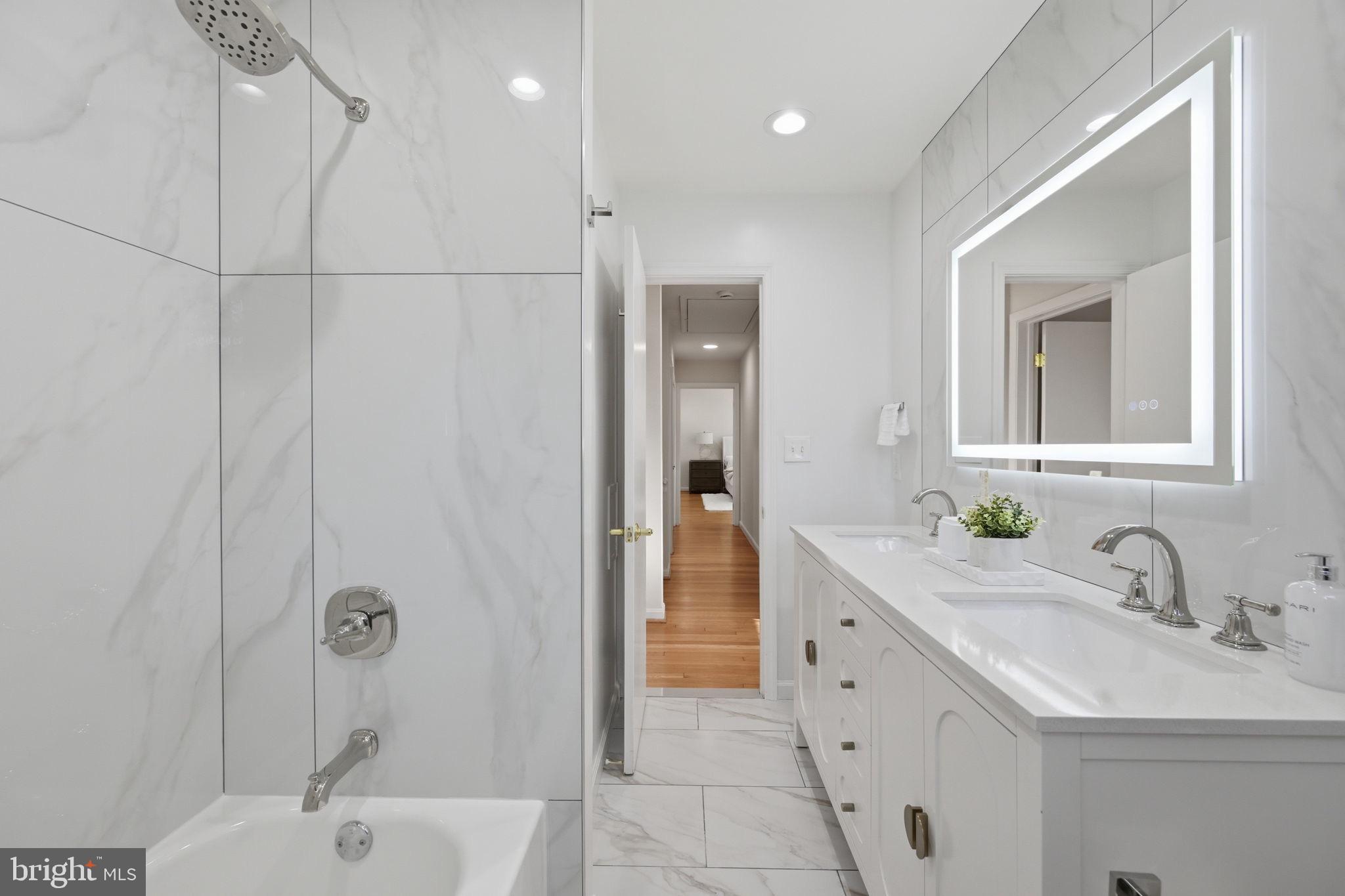 2827 Ellicott Street Northwest Washington, DC 20008 - Photo 50 of 56 a bathroom with a double vanity sink a mirror and a bathtub