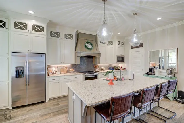 a kitchen with granite countertop a table chairs stainless steel appliances and wooden floor