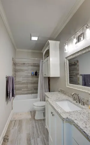 a bathroom with a granite countertop sink a toilet a mirror and shower