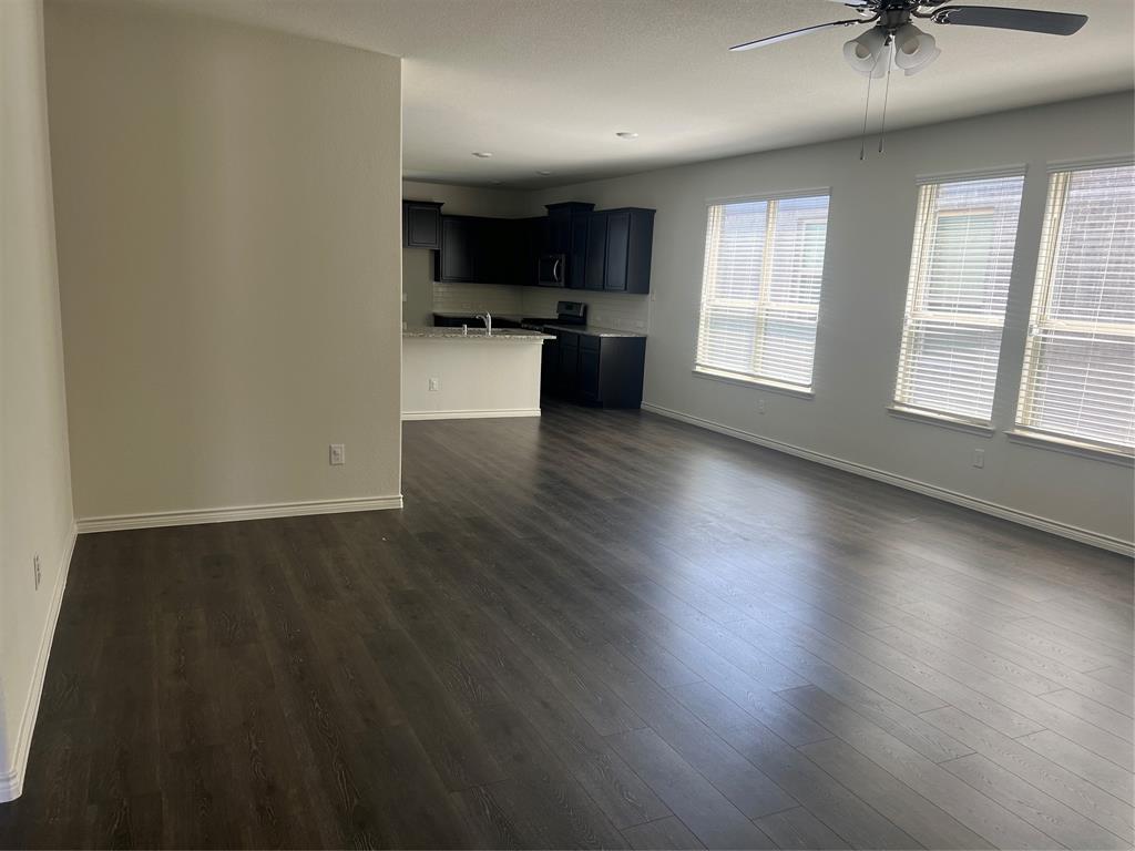1821 Ferguson Lane McKinney, TX 75071 - Photo 7 of 26 an empty room with wooden floor and a kitchen view