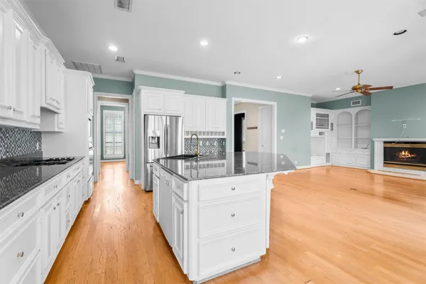 a large kitchen with stainless steel appliances kitchen island granite countertop a large kitchen island a stove a refrigerator a sink and dishwasher with white cabinets