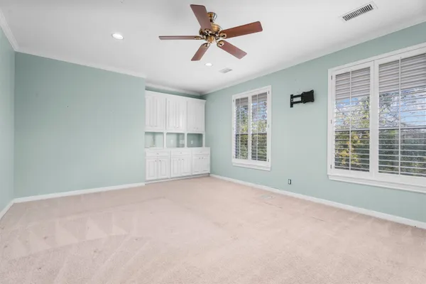 an empty room with windows and ceiling fan