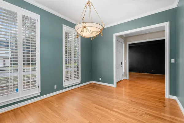 a view of an empty room with window and wooden floor