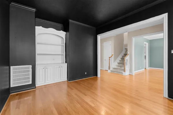 a view of an empty room with wooden floor and stairs