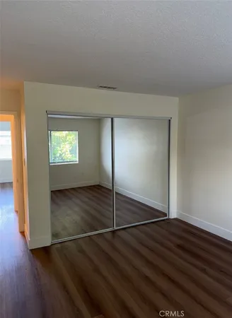 an empty room with wooden floor mirror and windows