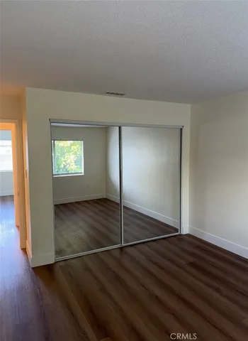 an empty room with wooden floor mirror and windows