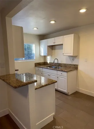 a kitchen with granite countertop a sink a stove and cabinets