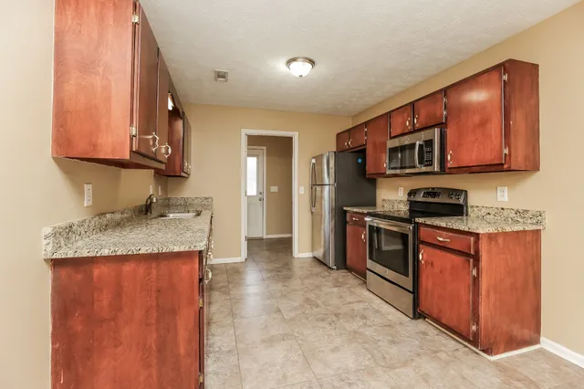 a kitchen with stainless steel appliances granite countertop a stove a sink and a microwave