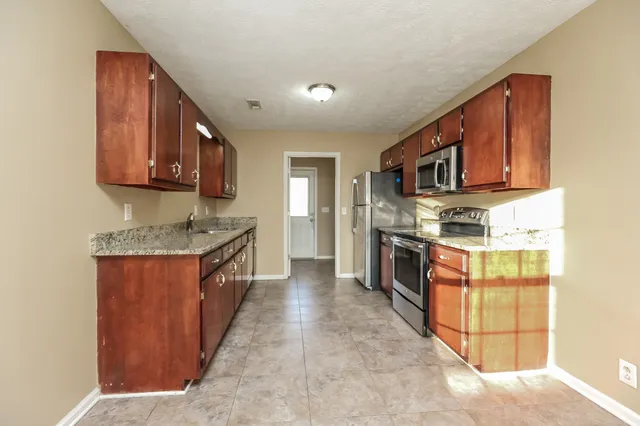 a kitchen with stainless steel appliances granite countertop a stove top oven a sink a counter space and cabinets