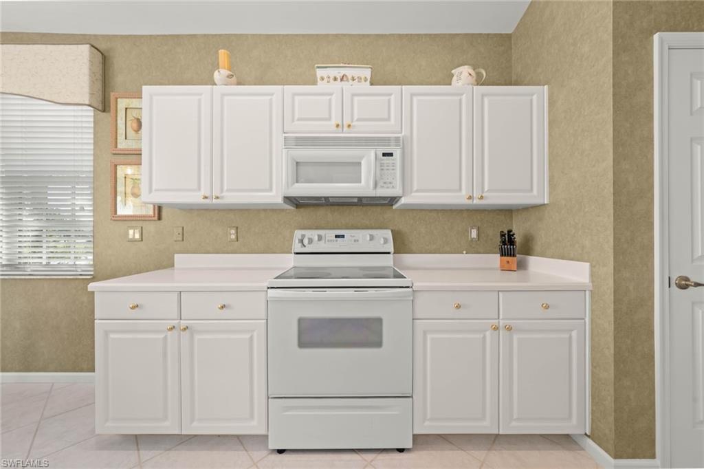 23101 Rosedale Drive, Unit 202 Estero, FL 34135 - Photo 14 of 49 a kitchen with white cabinets and white appliances