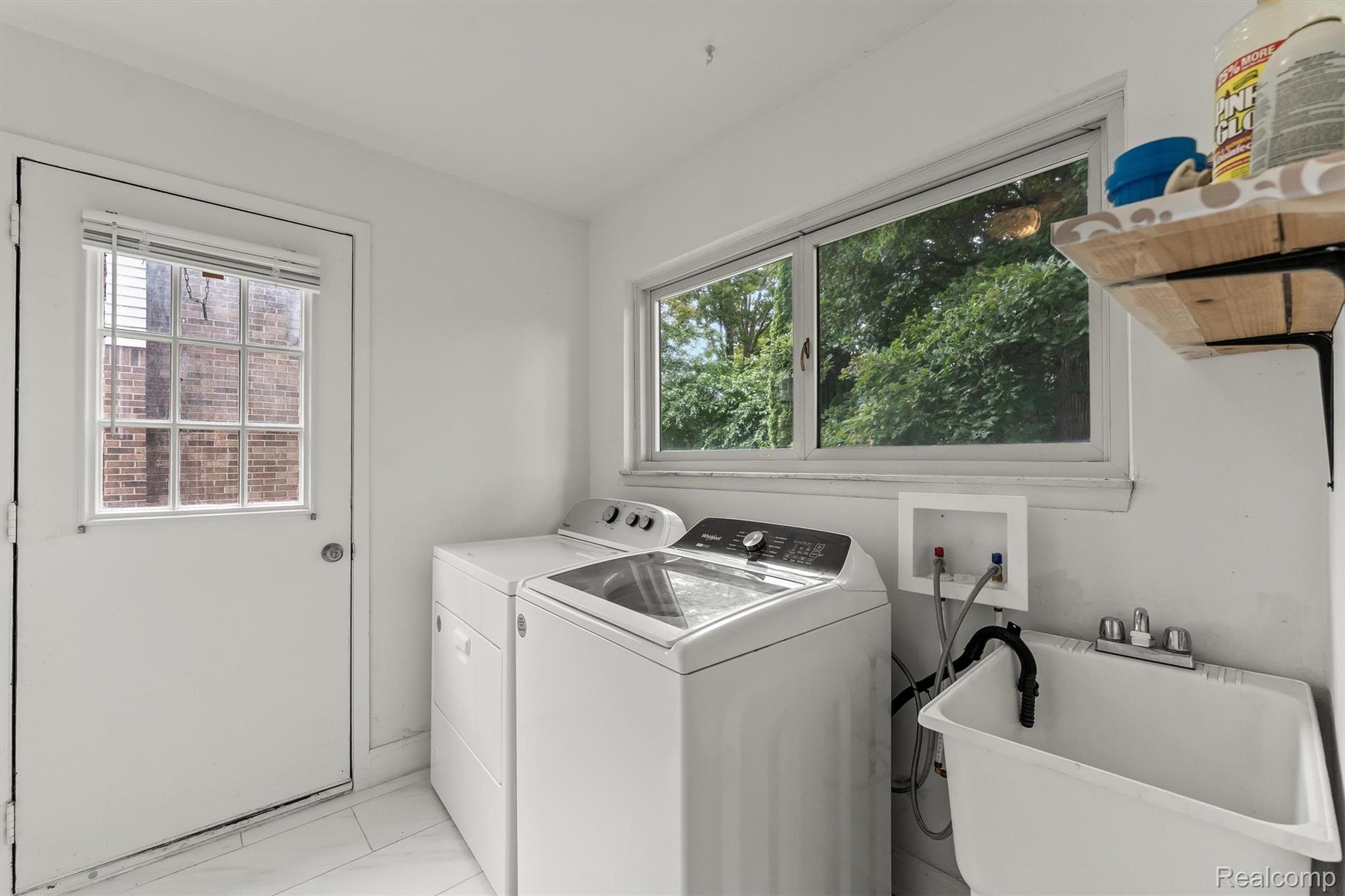 2118 Rutgers Drive Troy, MI 48085 - Photo 32 of 39 Dedicated laundry space featuring a utility sink, a large window, a windowed exterior door, and a wall-mounted wood shelf with black brackets