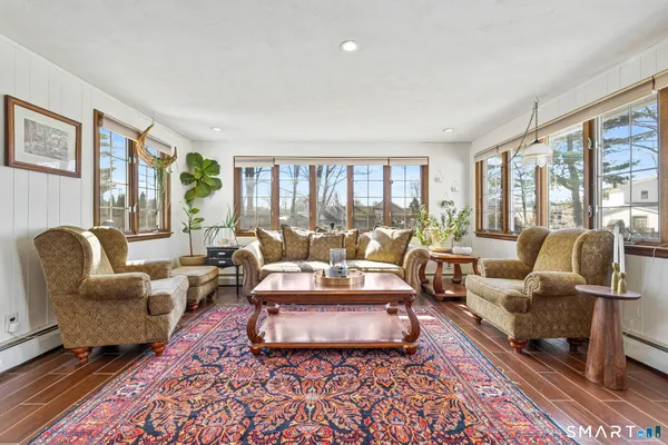 a living room with furniture large windows and wooden floor