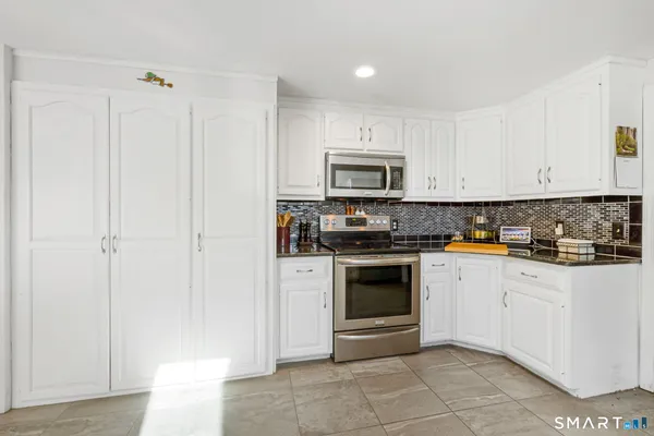 a kitchen with granite countertop white cabinets stainless steel appliances and a sink