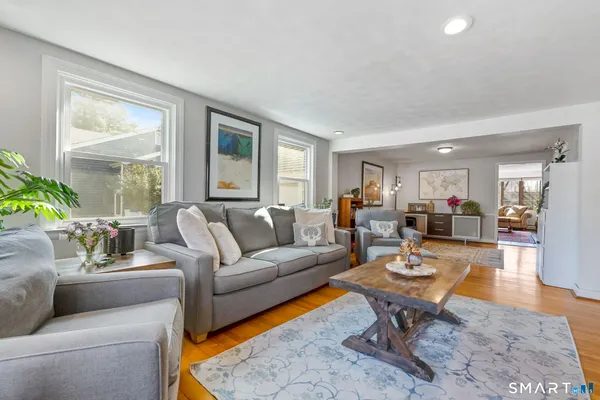 a living room with furniture a wooden floor and a large window