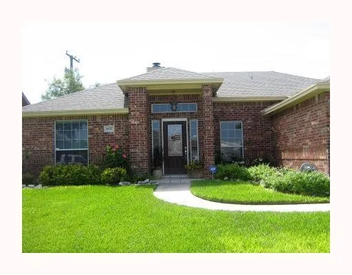 a view of a house with brick walls and a yard with plants