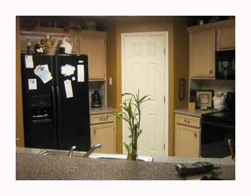 a kitchen with stainless steel appliances kitchen island granite countertop a refrigerator and cabinets