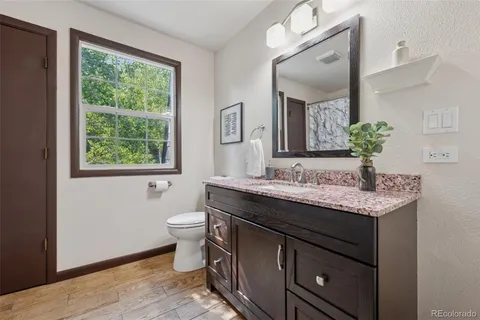 a bathroom with a granite countertop sink a toilet and a mirror