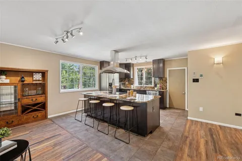 a view of a kitchen with kitchen island stainless steel appliances wooden floor and large window