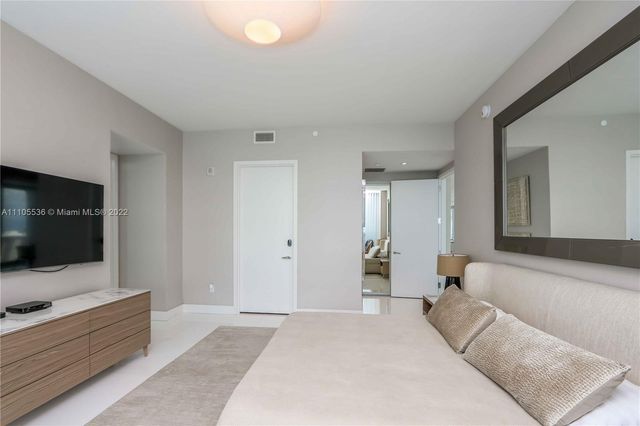 a spacious bedroom with a bed and a flat screen tv