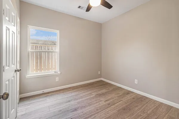 an empty room with a window and wooden floor