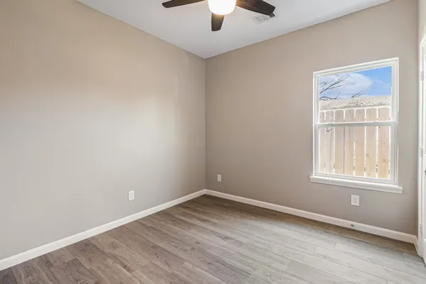 an empty room with windows and fan